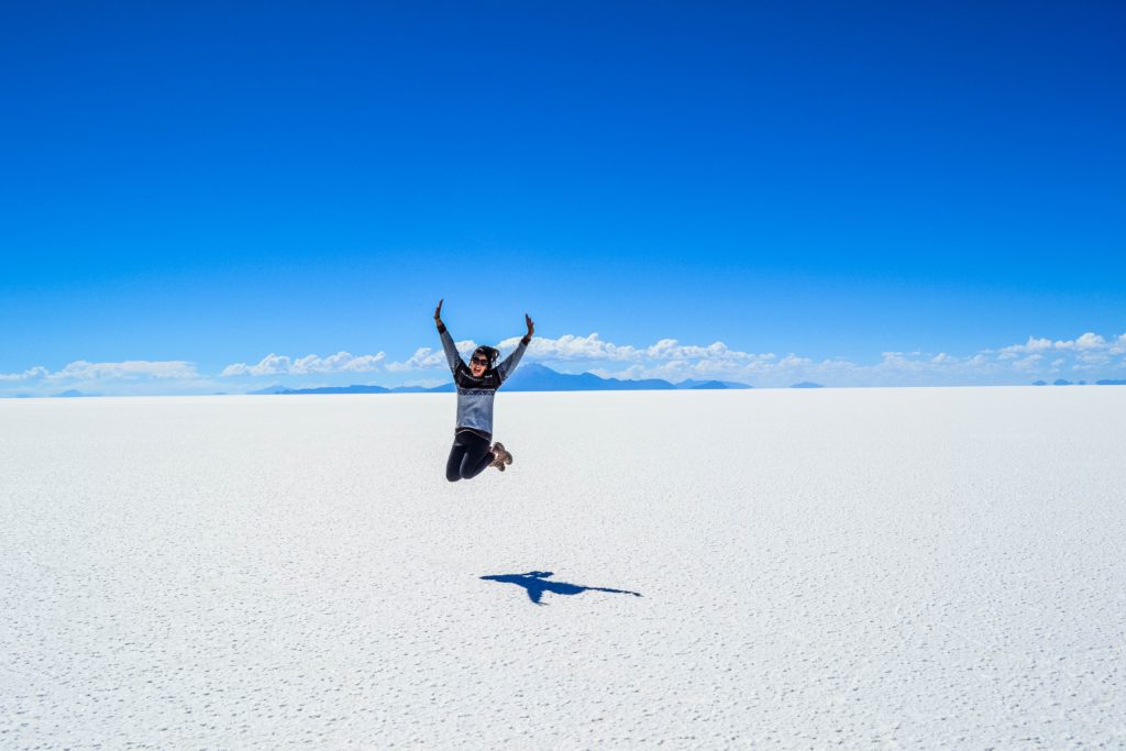 Person jumping on a white earth with blue skies above